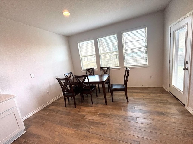 dining area featuring plenty of natural light, dark wood-style flooring, and baseboards