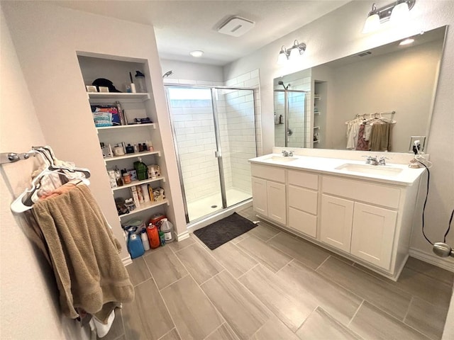 bathroom featuring a sink, a shower stall, double vanity, and a spacious closet