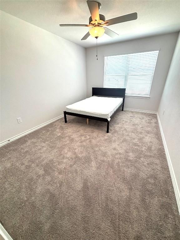 carpeted bedroom featuring baseboards and ceiling fan