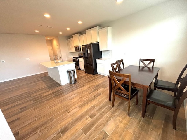 kitchen with stainless steel appliances, recessed lighting, wood finished floors, and white cabinetry