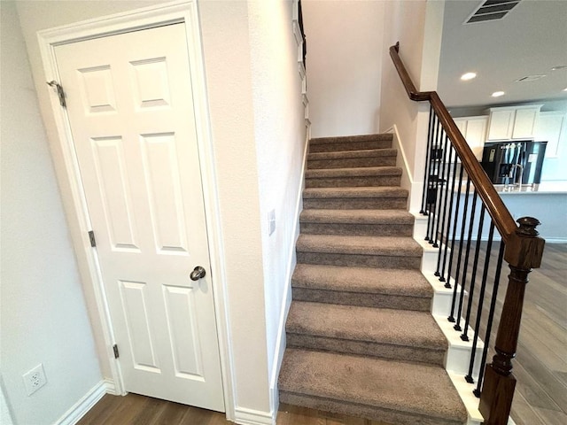 staircase featuring recessed lighting, baseboards, visible vents, and wood finished floors