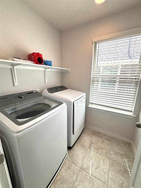 laundry area with separate washer and dryer, laundry area, baseboards, and light tile patterned floors