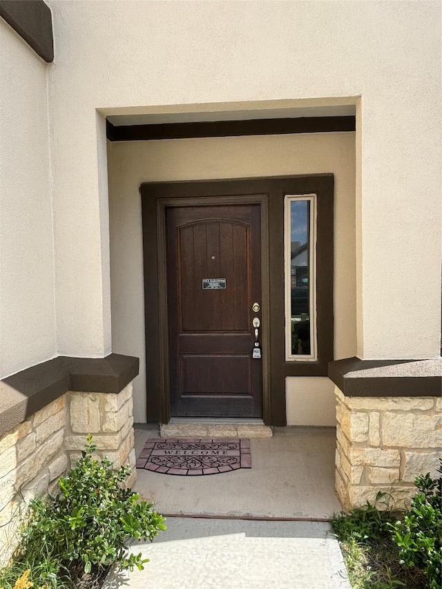 property entrance featuring stucco siding and stone siding