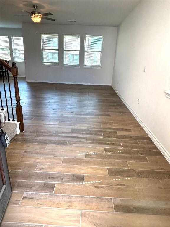 spare room featuring ceiling fan, baseboards, plenty of natural light, and wood finished floors
