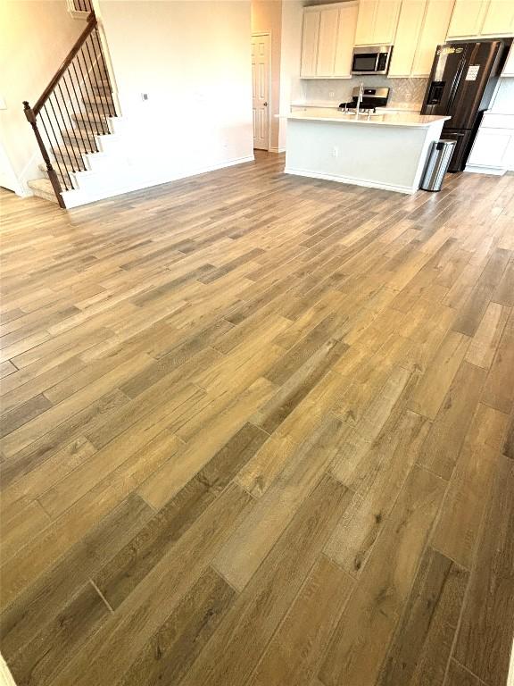 unfurnished living room featuring a sink, stairs, and wood finished floors