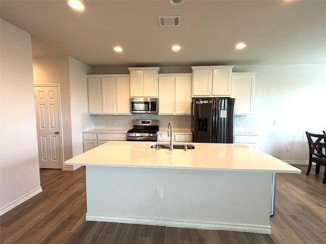 kitchen featuring appliances with stainless steel finishes, a sink, a kitchen island with sink, baseboards, and visible vents