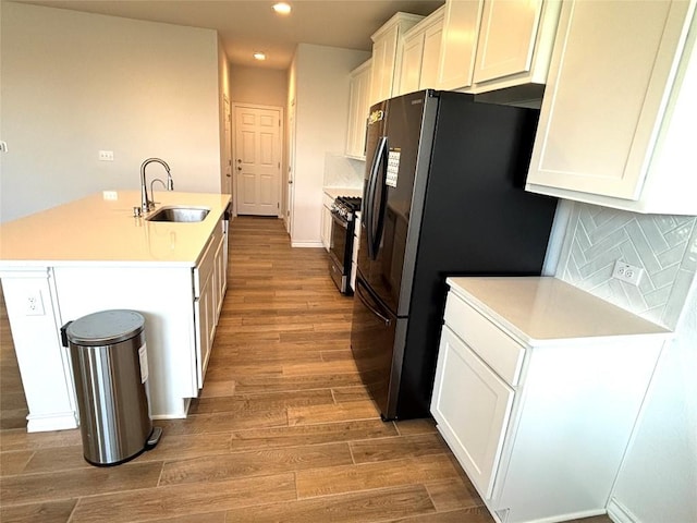 kitchen with a sink, light wood finished floors, recessed lighting, white cabinetry, and gas range