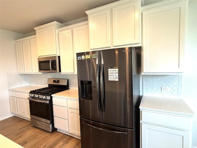 kitchen with light countertops, light wood finished floors, backsplash, and stainless steel appliances