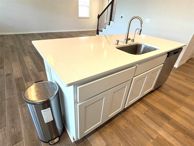 kitchen featuring a sink, light countertops, dark wood-style flooring, and an island with sink