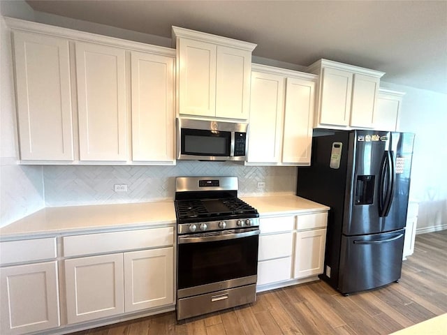 kitchen featuring appliances with stainless steel finishes, tasteful backsplash, light countertops, light wood finished floors, and white cabinetry