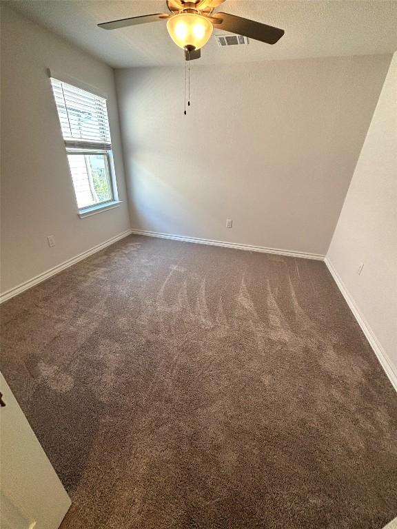 carpeted spare room with baseboards, a ceiling fan, and visible vents