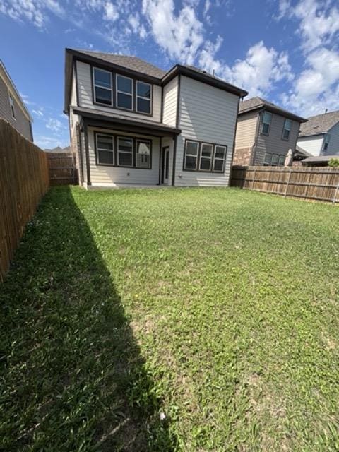 rear view of house with a fenced backyard and a yard