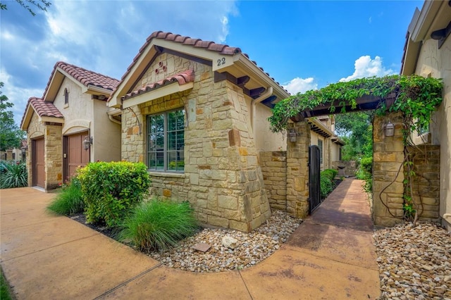view of side of property featuring a tiled roof, stucco siding, and stone siding