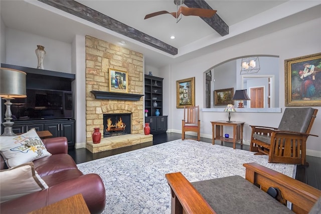 living room featuring a stone fireplace, wood finished floors, baseboards, ceiling fan with notable chandelier, and recessed lighting