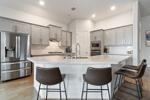 216 Vista Village Cv, Austin, TX 78738 - kitchen with appliances with stainless steel finishes, gray cabinetry, a sink, backsplash, and a breakfast bar area
