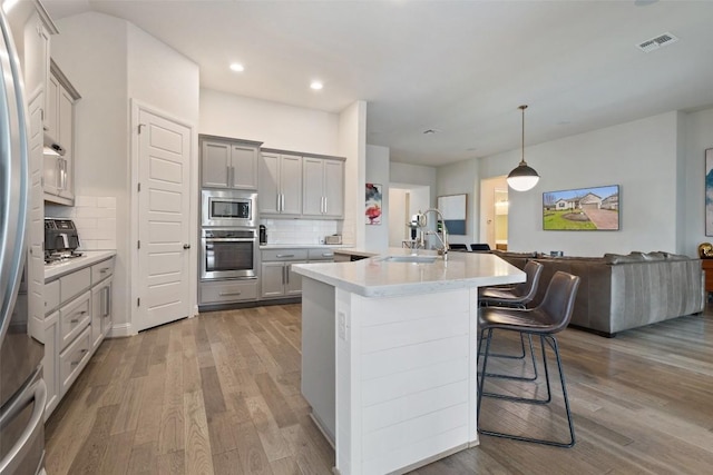 216 Vista Village Cv, Austin, TX 78738 - kitchen featuring appliances with stainless steel finishes, a sink, wood finished floors, decorative backsplash, and recessed lighting