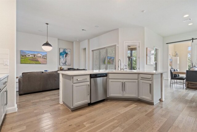 216 Vista Village Cv, Austin, TX 78738 - kitchen featuring stainless steel dishwasher, a sink, open floor plan, light countertops, and a barn door