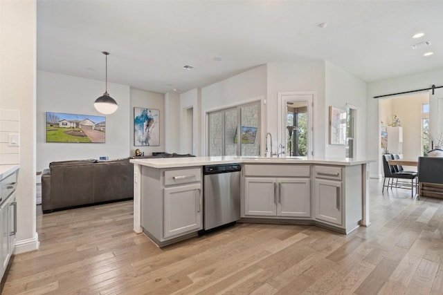 216 Vista Village Cv, Austin, TX 78738 - kitchen with stainless steel dishwasher, open floor plan, light countertops, a barn door, and light wood-style flooring