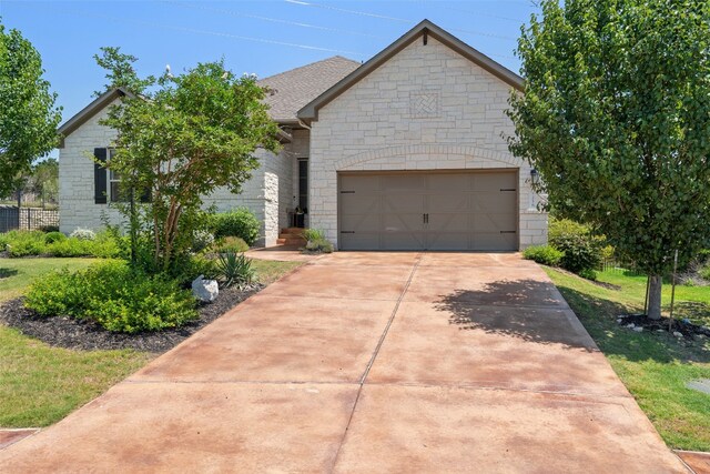 216 Vista Village Cv, Austin, TX 78738 - french country inspired facade featuring stone siding, concrete driveway, and an attached garage
