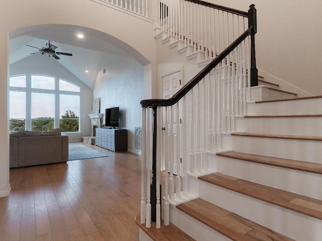 19200 White Horse Cv, Spicewood, TX 78669 - stairway featuring arched walkways, ceiling fan, hardwood / wood-style flooring, and high vaulted ceiling
