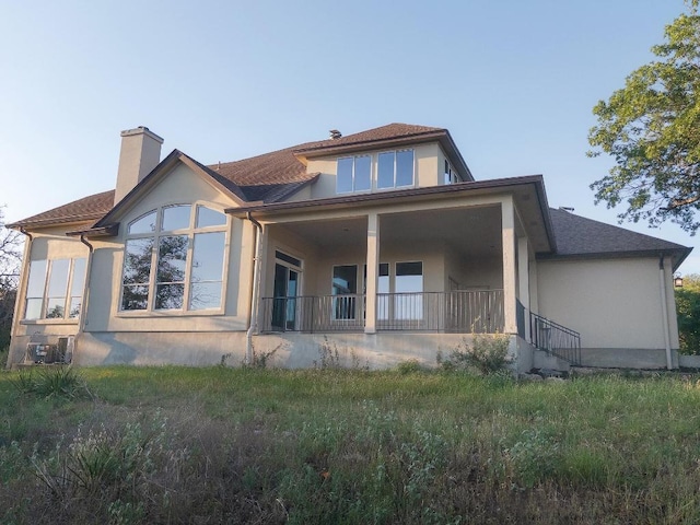 19200 White Horse Cv, Spicewood, TX 78669 - back of property featuring a shingled roof, stucco siding, and a chimney