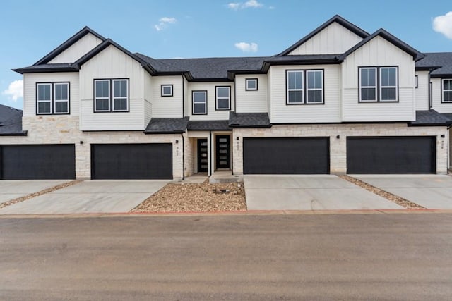 multi unit property featuring an attached garage, board and batten siding, driveway, and stone siding