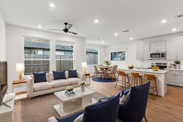 living area featuring recessed lighting, a ceiling fan, visible vents, and light wood-style floors