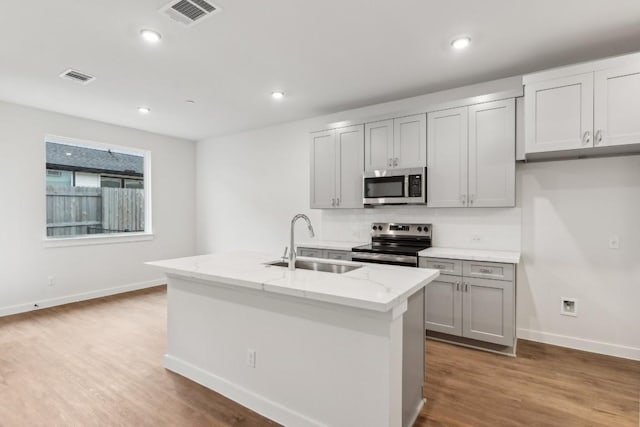kitchen featuring stainless steel appliances, visible vents, a sink, and wood finished floors
