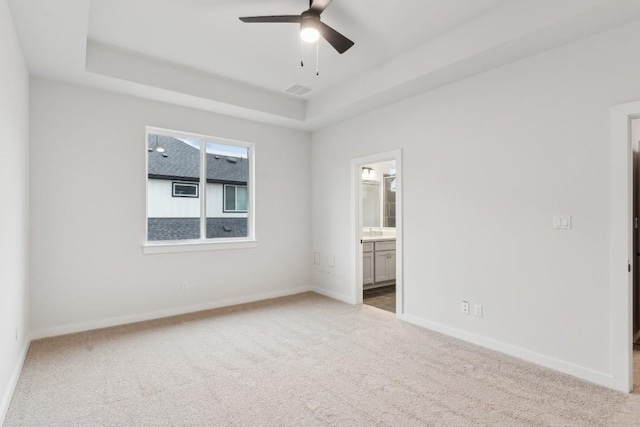 unfurnished bedroom featuring visible vents, baseboards, a raised ceiling, connected bathroom, and carpet