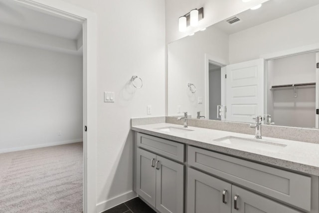 bathroom with double vanity, baseboards, visible vents, and a sink