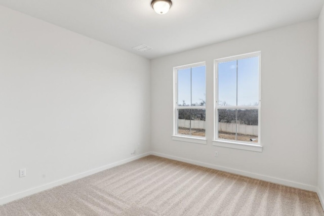 empty room featuring baseboards and light carpet