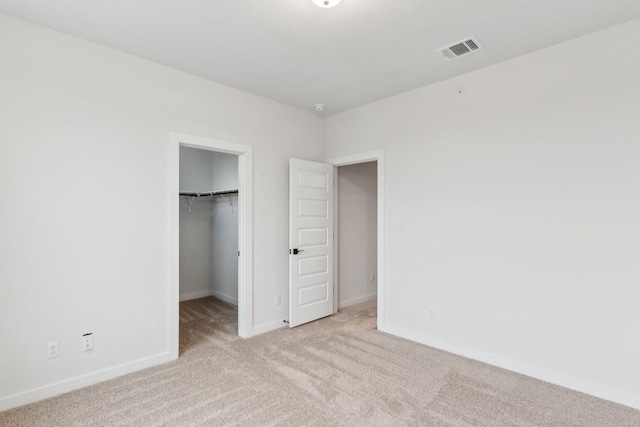 unfurnished bedroom with visible vents, carpet floors, a closet, baseboards, and a spacious closet