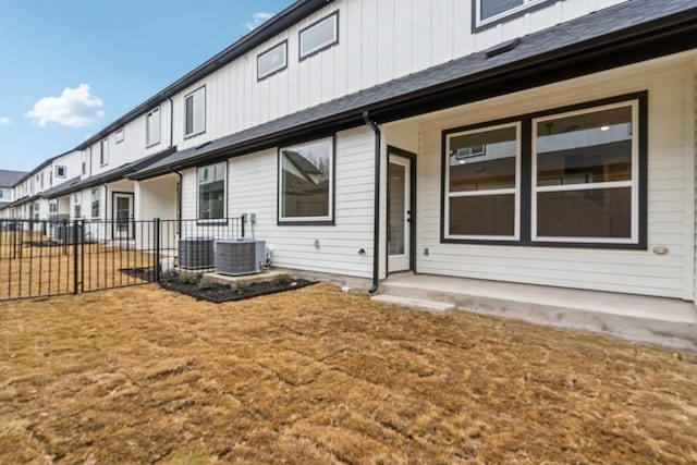 back of house featuring fence, central AC unit, and board and batten siding