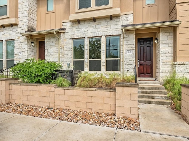 view of exterior entry featuring board and batten siding and stone siding