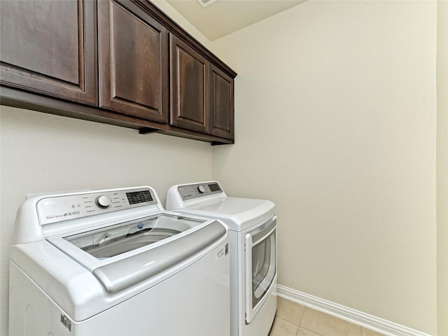 laundry area with washer and dryer, baseboards, light tile patterned floors, and cabinet space
