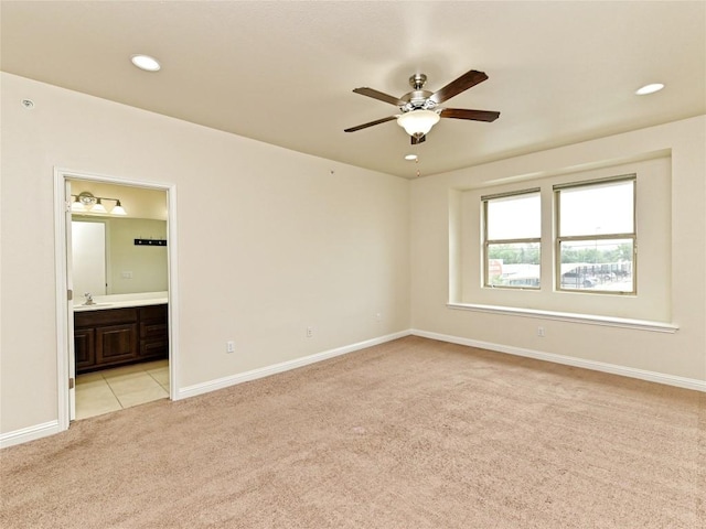 spare room featuring a ceiling fan, light colored carpet, a sink, baseboards, and recessed lighting