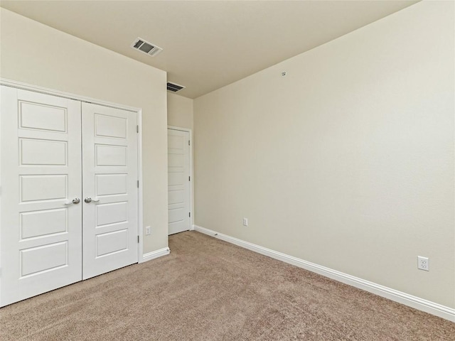 unfurnished bedroom featuring visible vents, carpet, baseboards, and a closet
