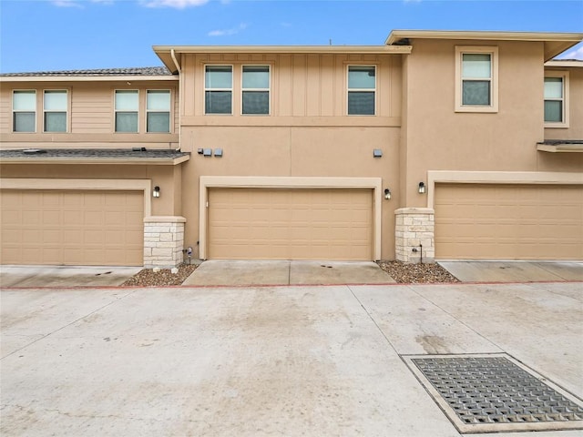 view of property featuring an attached garage, stucco siding, and stone siding