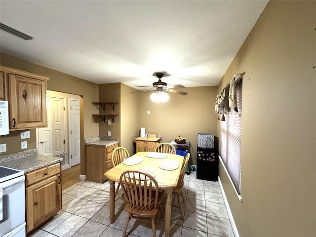 dining area with light tile patterned flooring, a ceiling fan, visible vents, and baseboards