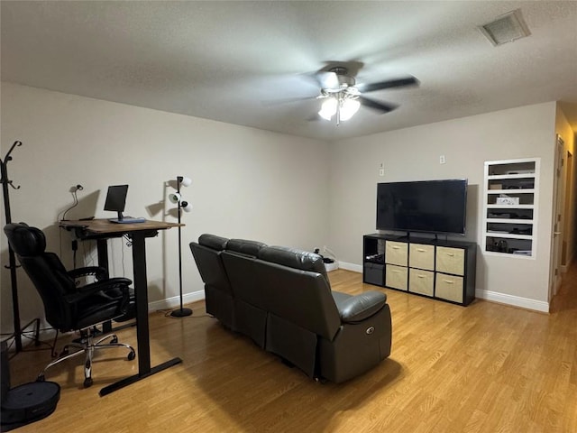living area with baseboards, ceiling fan, light wood finished floors, and visible vents
