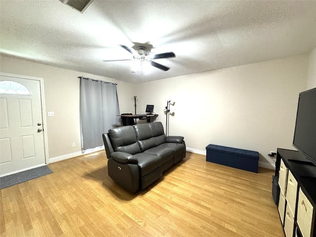 living area featuring baseboards, a textured ceiling, visible vents, and light wood-style flooring