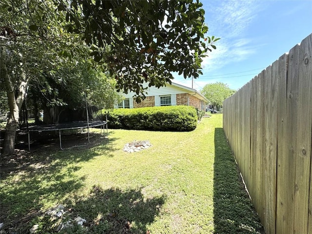 view of yard with fence and a trampoline
