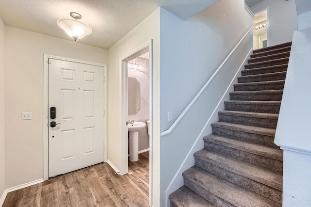 9504 Southwick Dr, Austin, TX 78724 - entrance foyer featuring wood finished floors, stairs, baseboards, and a textured ceiling