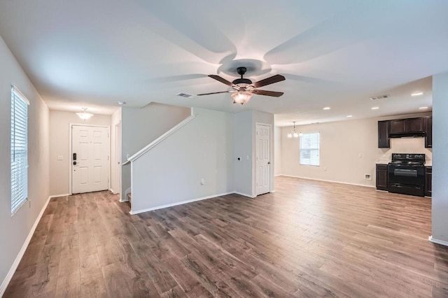9504 Southwick Dr, Austin, TX 78724 - unfurnished living room with wood finished floors, a ceiling fan, baseboards, stairs, and a chandelier