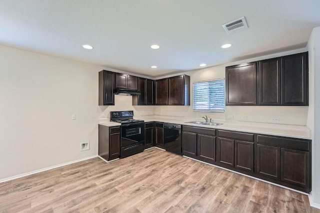 9504 Southwick Dr, Austin, TX 78724 - kitchen featuring black appliances, a sink, under cabinet range hood, light wood-style flooring, and light countertops