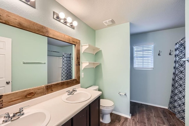 9504 Southwick Dr, Austin, TX 78724 - full bath with toilet, wood finished floors, a textured ceiling, double vanity, and a shower with curtain