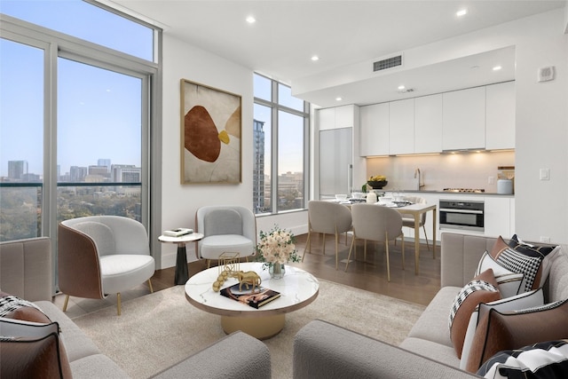 living room with recessed lighting, visible vents, floor to ceiling windows, and wood finished floors