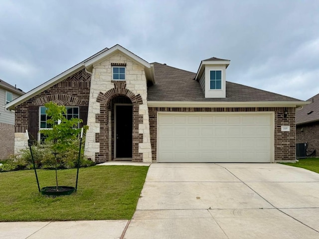 french country home with a garage, a front yard, roof with shingles, brick siding, and driveway