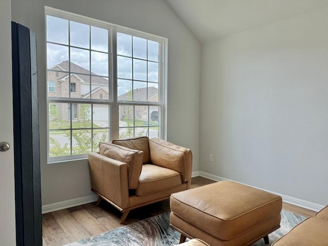 living area featuring baseboards, vaulted ceiling, and wood finished floors