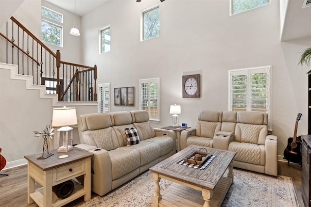 living area with stairs, a high ceiling, baseboards, and wood finished floors